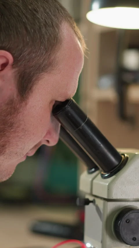 Technician Observing Under Microscope with Red Wire in Laboratory Video stock 310489345