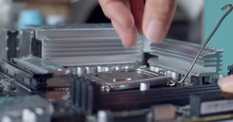 A technician opens the CPU retention lever on a motherboard. Stock Footage 311939123