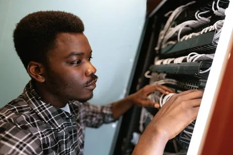 Technician organizing cables in a server room during daylight in a modern Stock Photos