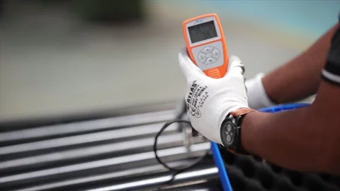 A technician performing a coating thickness test on industrial pipes using Stock Footage 328084544
