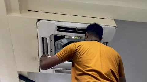 Technician performing maintenance on a ceiling-mounted cassette type AC Stock Footage 337458338
