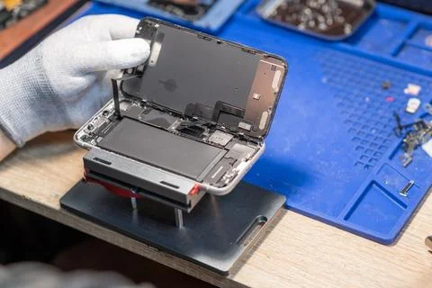 A technician performs a battery replacement on a mobile device, showcasing .. Stock Photos
