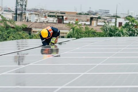 Technician performs maintenance on solar panels in an urban setting during .. Stock Photos