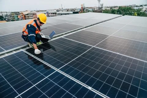 Technician performs maintenance on solar panels on a rooftop in an urban ar.. Stock Photos