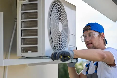 Technician performs service maintenance of a remote air conditioner Stock Photos