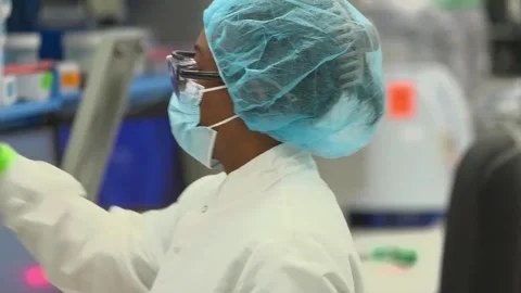 A technician pipettes into a sample rack in a crime laboratory testing DNA Stock-Footage 345299140