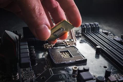 Technician plug in CPU microprocessor to motherboard socket. Workshop background Stock Photos
