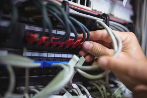 Technician plugging patch cable in a rack mounted server Stock Photos