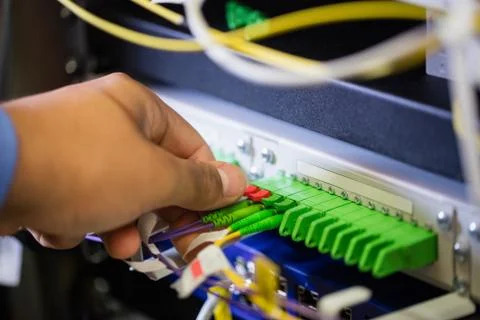 Technician plugging patch cable in a rack mounted server Stock Photos