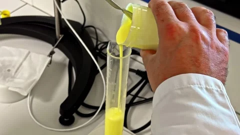 Technician Pouring Yellow Liquid into Laboratory Measuring Cylinder Stock Footage 341540157