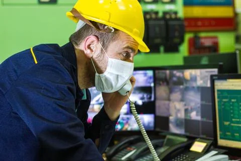 Technician with protective mask working on computer and doing telephone call 스톡 사진