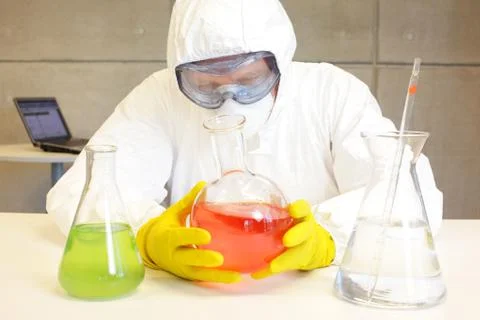 Technician in protective uniform working with substance in lab Stock Photos