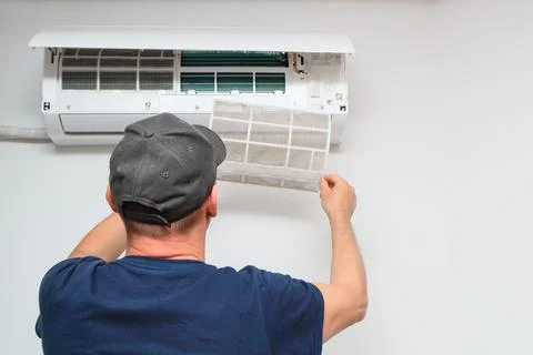 Technician pulling out a dirty filter from indoor air conditioner unit close  Stock Photos