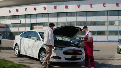 Technician in red overalls examines engine problems with diagnostic computer, Stock Footage 312515901
