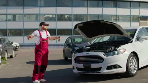 Technician in red overalls using diagnostic computer to identify engine 스톡 동영상 312516314