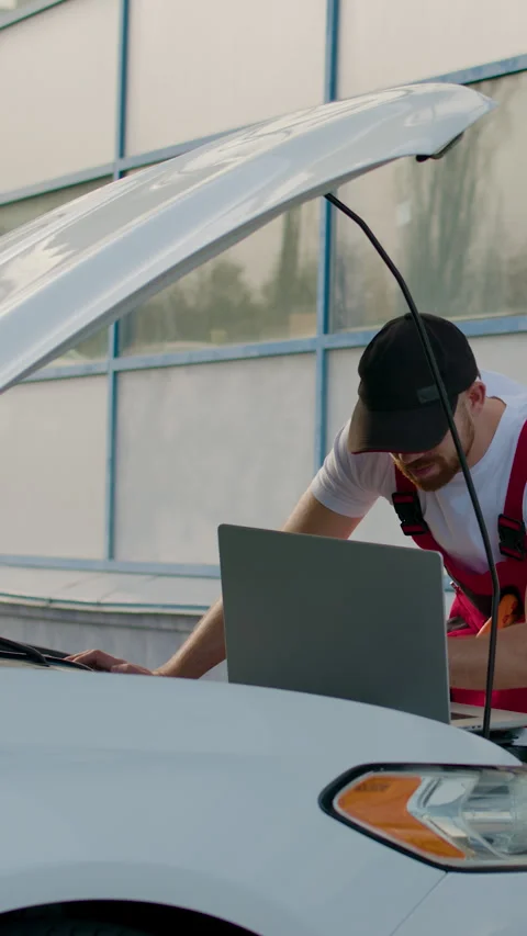 Technician in red overalls using diagnostic computer to identify engine problems Stock Footage 320394406
