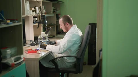 Technician Relaxing and Examining Circuit Under Microscope in Lab Stock Footage 282648818