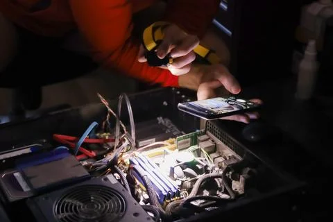 Technician repairing internal computer hardware with smartphone Stock Photos