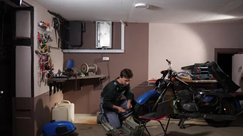 Technician repairing a motorcycle in a workshop, checking technical data on a 스톡 동영상 342768285
