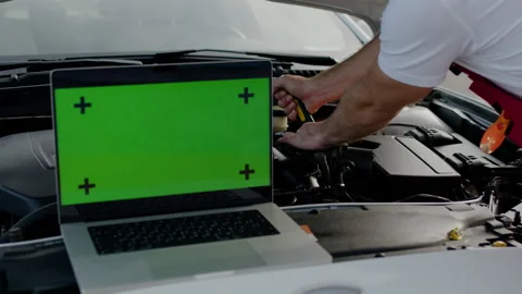 Technician repairs car engine under hood laptop green chroma key screen Stock Footage 274417457