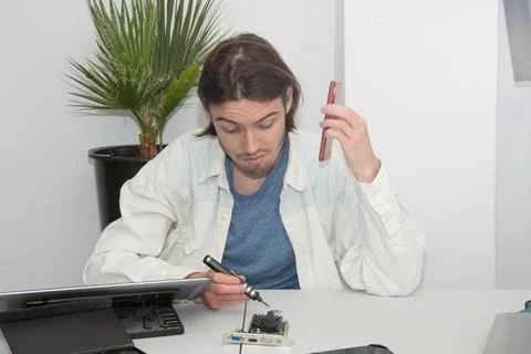 A technician repairs computer equipment using electronic components and tools Stock Photos