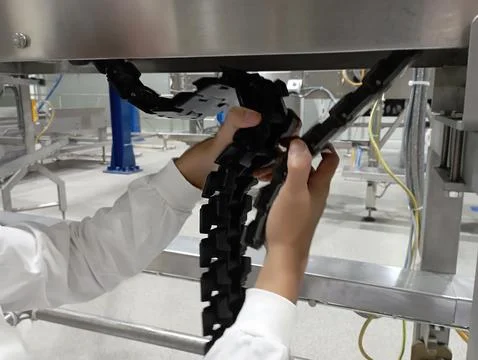 A technician is replacing a broken plastic conveyor with a new one Foto stock