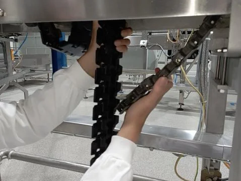 A technician is replacing a broken plastic conveyor with a new one Foto stock