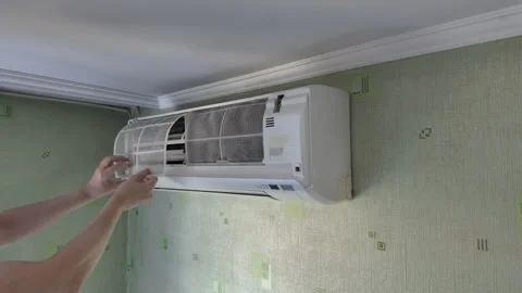 Technician replacing dusty mesh filter in wall mounted air conditioner unit.. Stock Footage 340631481