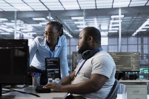 Technician requesting help from manager while working on computer in data center 库存照片