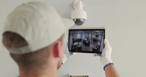 Technician Reviewing CCTV Camera Feed on Tablet During Security Setup Indoors Stock Footage 345805156