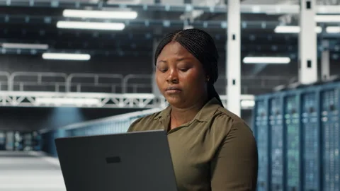 Technician in server farm using laptop to upgrade rigs Stock Footage 317203784