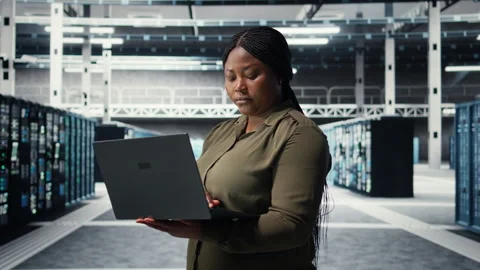Technician in server farm using laptop to upgrade rigs Stock Footage 317204350