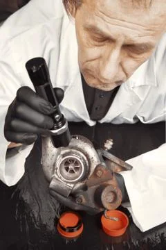 Technician service man examinating unmounted turbocharger for overhaul Stock Photos