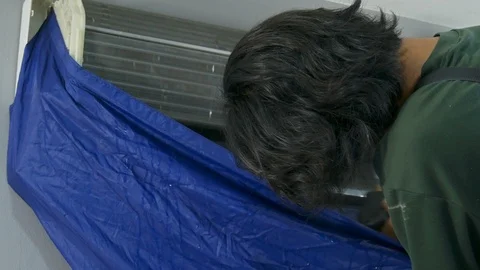 Technician service using water spray are cleaning the air conditioner indoors. Stock Footage 119884050