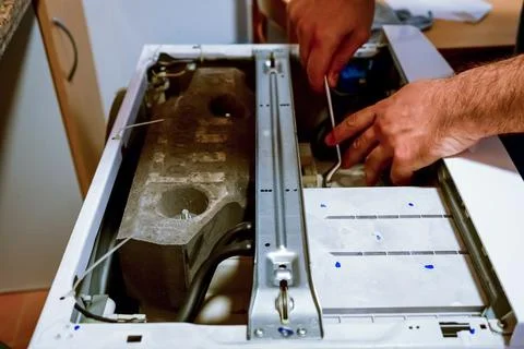 Technician servicing washing machine using pipe wrench. Stock Photos