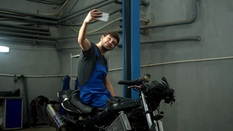 Technician sits on motorcycle and makes a photo Stock Footage 124259570
