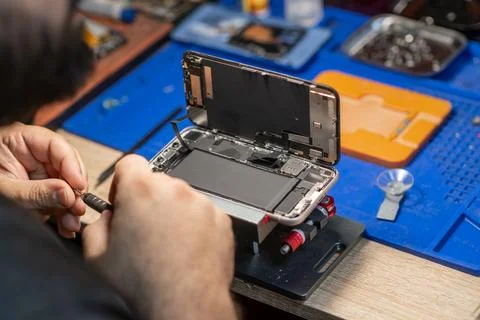 A technician skillfully disassembles a smartphone to replace its battery in a Foto stock
