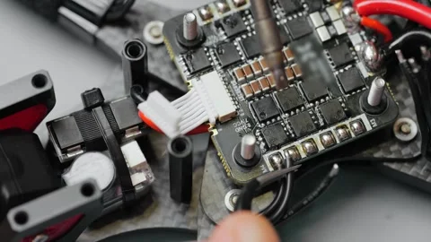 Technician soldering components onto circuit board of disassembled fpv drone Stock Footage 307863318