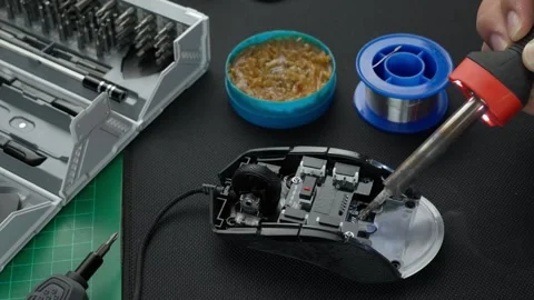 Technician soldering electronic components of a mouse with soldering iron Stock Footage 275400393