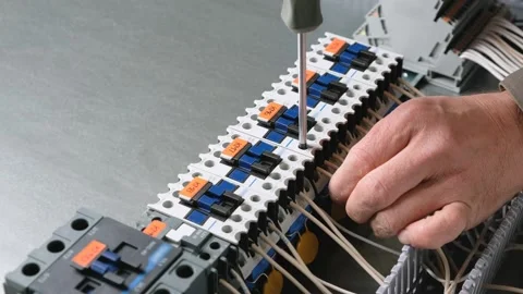 Technician сonnecting wire to the relay. Assembly of the control cabinet. Stock Footage 243628934
