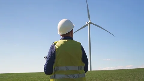 Technician standing near wind mill and making notes in tablet pr Stock Footage 113998697