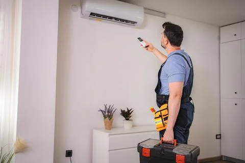 Technician testing air conditioning with remote control Stock Photos