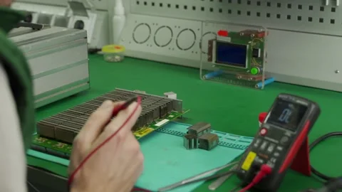Technician testing the circuit board with multimeter. Engineer repairing bitcoin Stock Footage 156550558