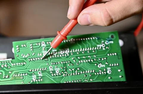 Technician Testing Circuit Board with Multimeter Probe Close-up Foto stock