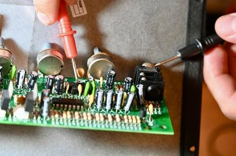 Technician Testing Circuit Board with Multimeter Probe Close-up 写真素材