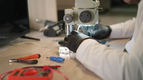 Technician Testing Circuit Under Microscope with Voltmeter in Lab Video stock 281372029