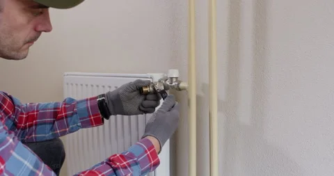 Technician tests fits ball valve on radiator inlet before install Stock Footage 322010742