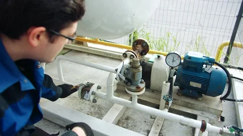 A technician turns a valve handle to pump propane through the pipes outdoors Stock Footage 313233815