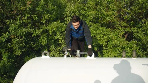 A technician in a uniform climbs onto barrel to perform professional inspection 库存影片 313233961