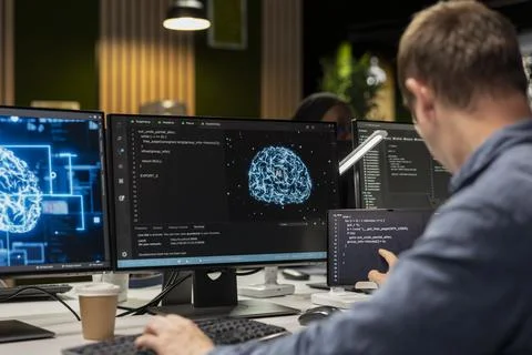 Technician uses computer in tech startup office to develop applications using AI 写真素材